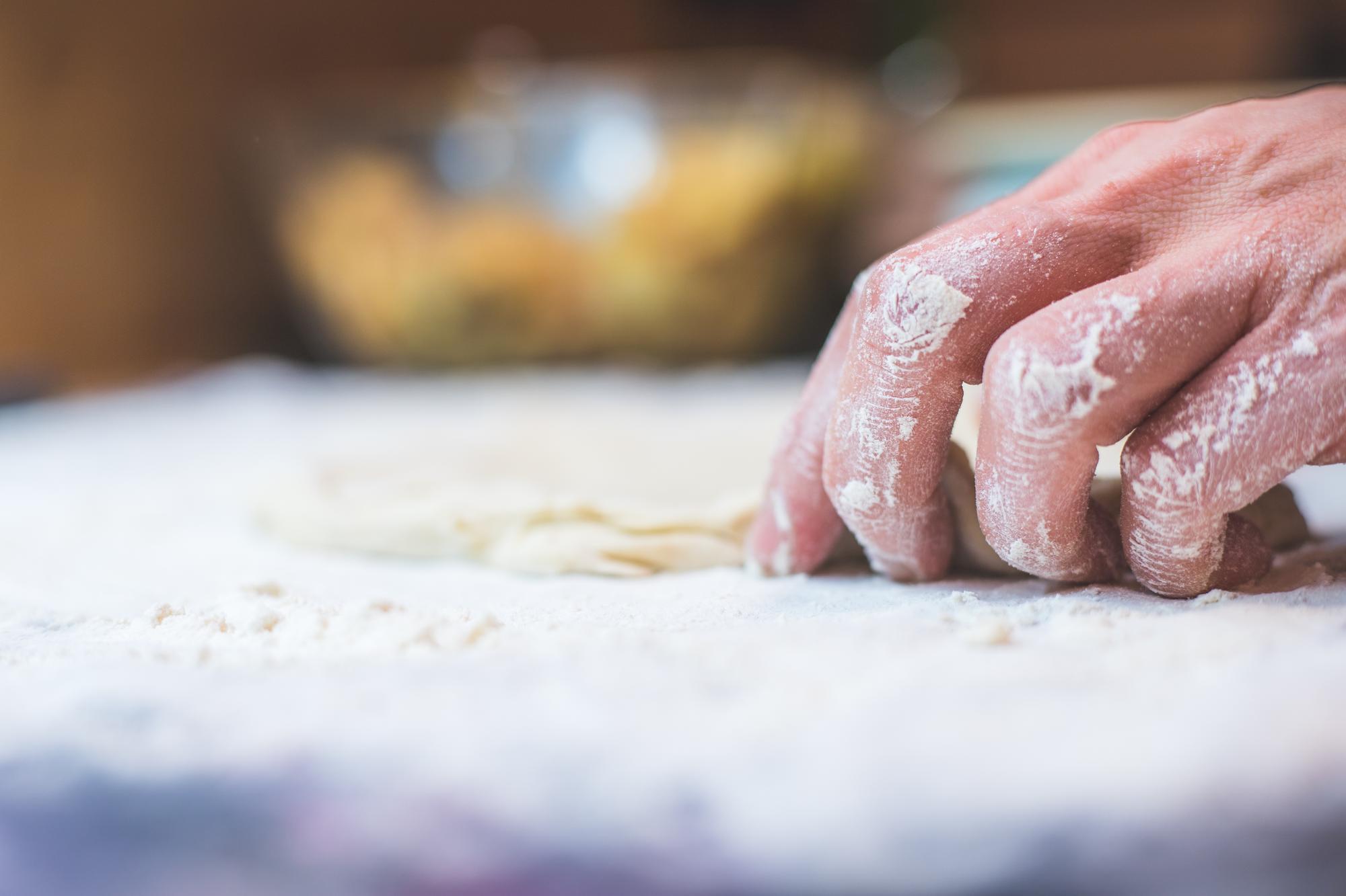 Close-up of hands kneading dough on a floured surface